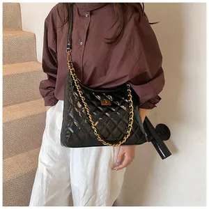 Close-up of black quilted shoulder bag with gold chain and square metal lock detail