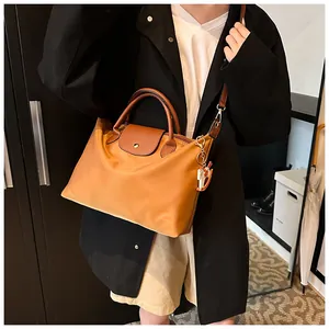 Detail of camel nylon tote bag with leather flap, handles and horse charm accessory