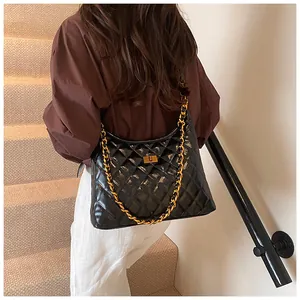 Detail view of black quilted faux leather shoulder bag with gold chain and metal clasp