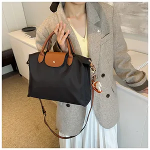 Close-up of black nylon tote bag with brown leather handle and white horse charm