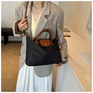 Lifestyle shot of black nylon tote bag with brown leather handles worn by a model