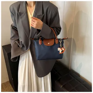 Detail of navy nylon tote bag with brown leather handles and decorative horse charm