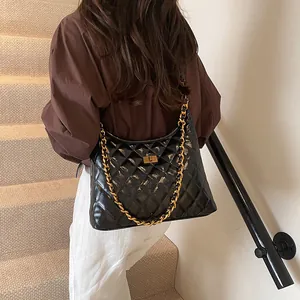 Chic black quilted diamond pattern shoulder bag with gold chain strap on a model