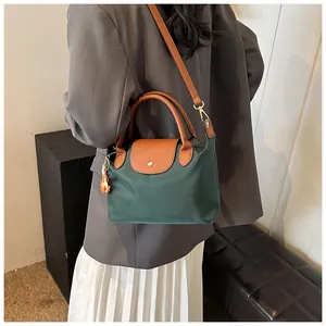 Back view of model wearing a green and brown contrast tote bag with a small bird charm