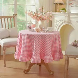 Pink gingham round tablecloth with elegant ruffled edges in a rustic home setting