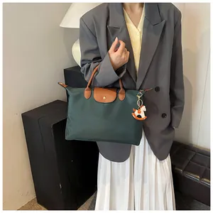 Detail of dark green nylon tote with brown leather handles and a horse charm