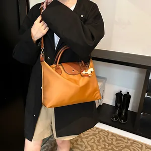 Large caramel nylon tote bag with leather handles and horse charm on a female model