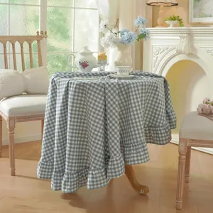Blue and white checkered cotton round tablecloth with ruffled edges in a warm home setting