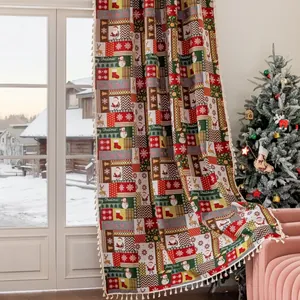 Detail van rode kerstgordijnen met feestelijke patchworkpatronen en witte pompon-kwastjes