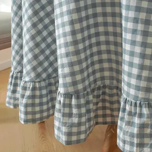 Close-up of blue and white gingham cotton tablecloth featuring elegant ruffled hem edges