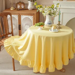 Close-up of light yellow ruffled round tablecloth with premium cotton linen texture