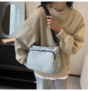 Vue détaillée du sac bandoulière en nylon bleu clair avec design multi-poches et sangle