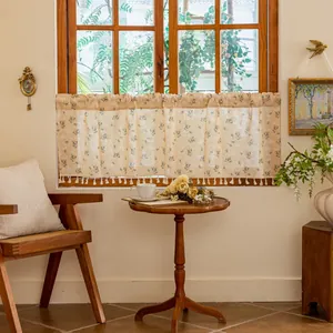 Detail of vintage floral coffee curtain with cotton tassels on a beige linen fabric
