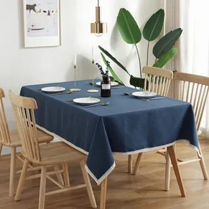 Detail of dark blue linen tablecloth featuring white lace fringe trim and geometric texture