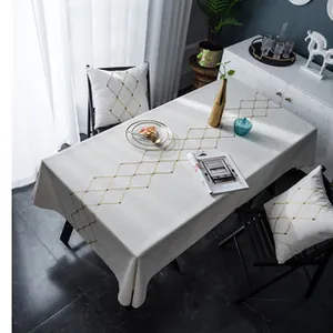 Close-up of beige cotton linen tablecloth with golden diamond lattice and matching cushions