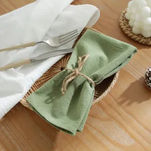 Groene katoenen placemat met henneptouw en witte stiksels op een rotan dienblad