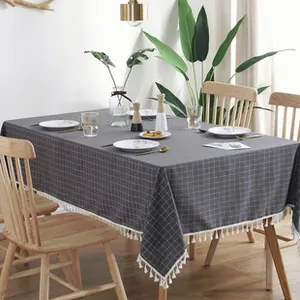 Close-up of dark grey checkered tablecloth with decorative white fringe on a dining table