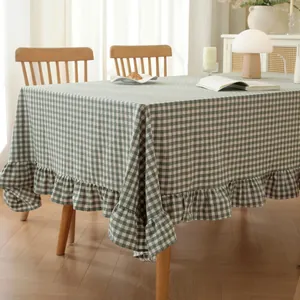 Detailed close-up of dark green plaid tablecloth with ruffle edges on wooden table