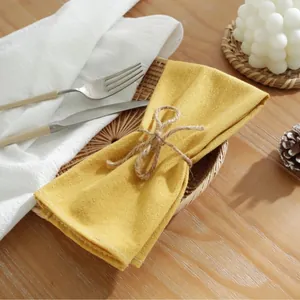 Geel katoenen servet met jute strik op rotan dienblad voor elegante tafelstyling