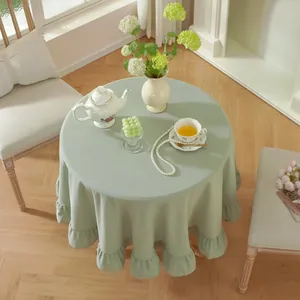 Detail of light green round tablecloth with elegant ruffled edges and washed cotton texture
