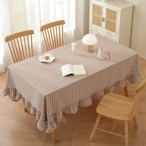 Detail of coffee plaid cotton tablecloth with ruffled edges on a wooden table