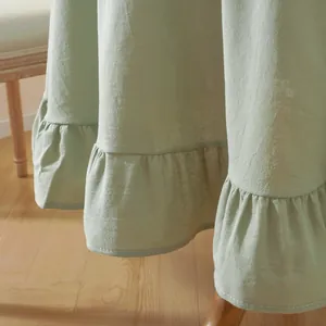 Detail of light green ruffled cotton skirt hem showing natural fabric texture and stitching