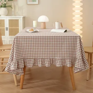 Detail of coffee plaid cotton tablecloth featuring elegant ruffled edges on a wooden table