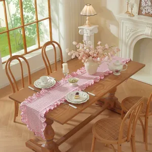 Franse vintage roze geruite tafelloper met ruches op een rustieke houten eettafel