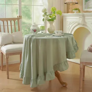Detail of light green round tablecloth with elegant ruffled edges and soft fabric drape