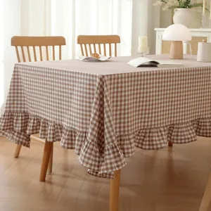 Detail of checkered cotton tablecloth with decorative ruffled edges in a warm home setting