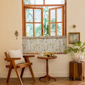 Detailed view of floral café curtain with blue green patterns and elegant white tassels