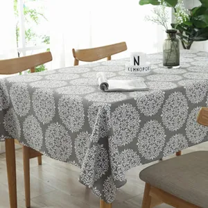 Detail of grey Nordic tablecloth with white damask pattern and elegant drape on wood table