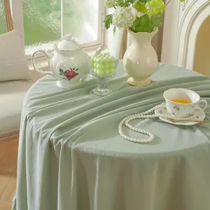 Close-up of sage green washed cotton tablecloth fabric with natural texture and soft drape