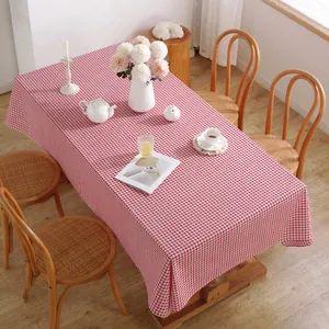 Détail de la nappe à carreaux vichy rouge et blanc avec franges sur table en bois