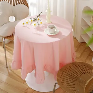 Detailed view of pink round tablecloth featuring elegant ruffled edges on a white table