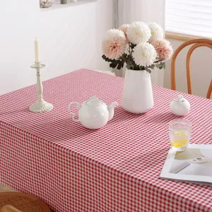 Détail d'une nappe à carreaux rouge et blanc avec pompons dans un décor chaleureux