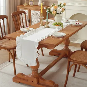 Minimalistische witte tafelloper met ruches op een lange houten eettafel binnen