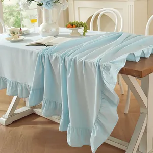 Détail d'une nappe en coton lavé bleu clair avec d'élégants bords à volants sur la table