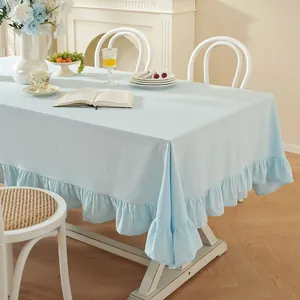 Détail d'une nappe en coton bleu clair avec bordure à volants et texture de tissu doux