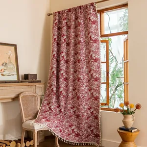Detail van rood jacquard gordijn met bloemen en franjes aan houten raamkozijn
