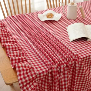 Red and white gingham cotton tablecloth with elegant ruffled edges on a wooden dining table
