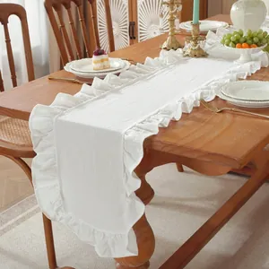 Minimalistische witte tafelloper met ruches op een rustieke houten eettafel