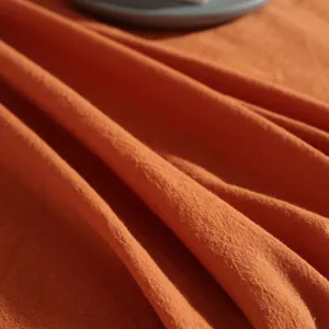 Close-up of orange washed cotton fabric showing natural texture and soft folds
