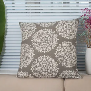 Taupe cotton linen throw pillow cover with white mandala pattern on a beige sofa