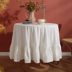 Close-up of elegant white washed cotton round tablecloth with ruffled hem details