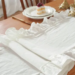 Detail van witte tafelloper met ruches en rustieke linnen textuur voor bruiloften en feesten