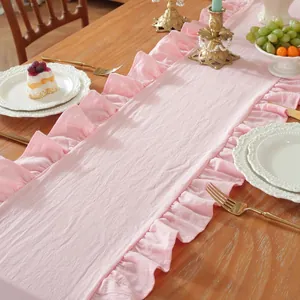 Detail van lichtroze tafelloper met elegante ruchesranden en geweven textuur