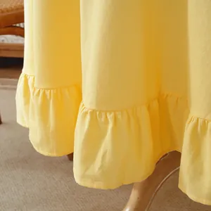 Detail of soft yellow cotton dress featuring a ruffled hem and textured fabric finish