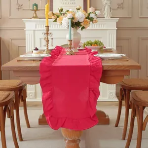 Detail van rode katoenen tafelloper met franjes in Franse retrostijl op houten tafel