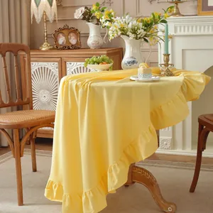 Detail of round mustard yellow tablecloth with elegant ruffle edge in French retro style